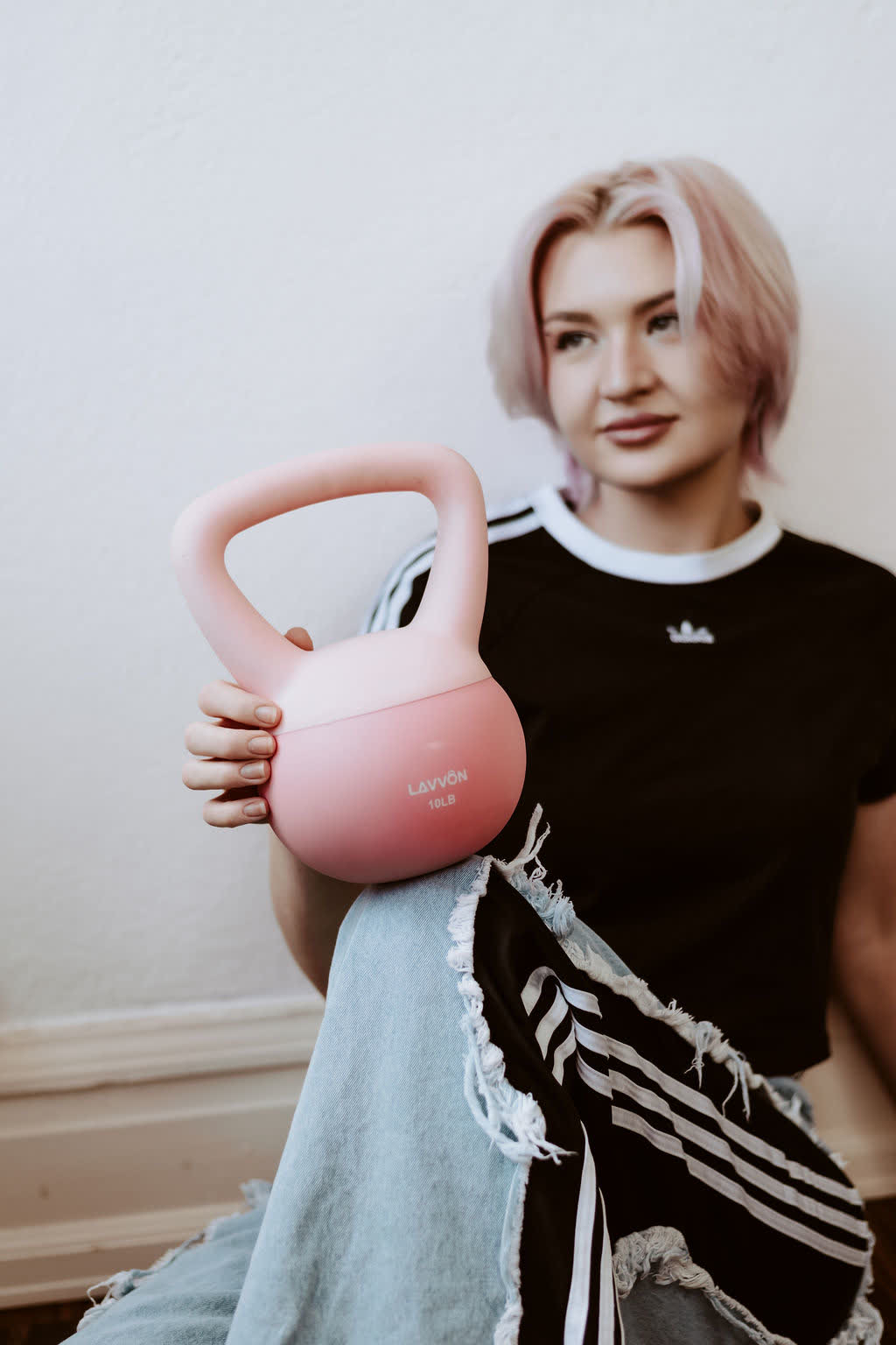 B. in a black adidas t-shirt sitting with a pink kettlebell