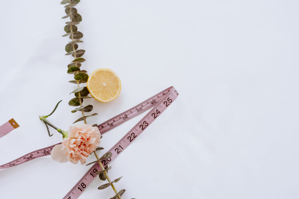 Pink measuring tape with eucalyptus and a lemon half